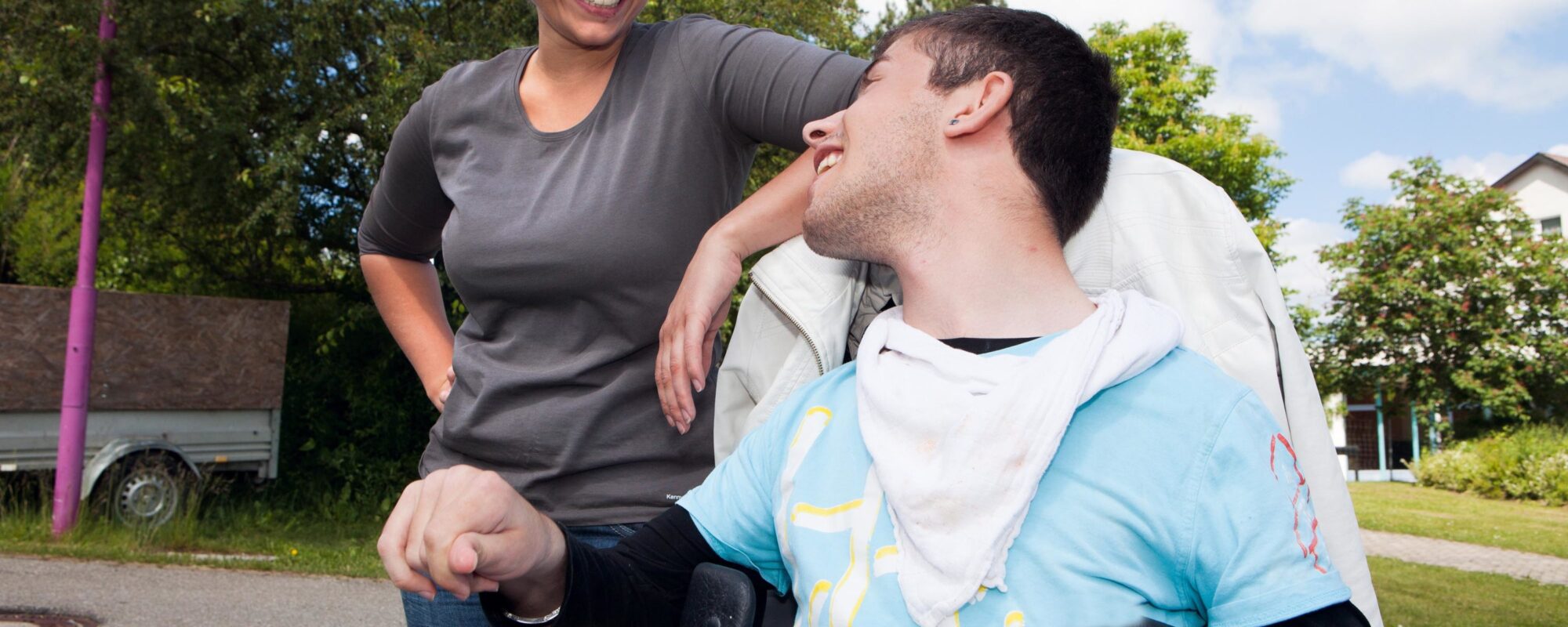Mann im Rollstuhl lacht mit Frau neben ihm