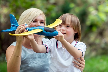 Eine pädagogische Fachkraft und ein Kind lassen einen Spielzeugflieger fliegen
